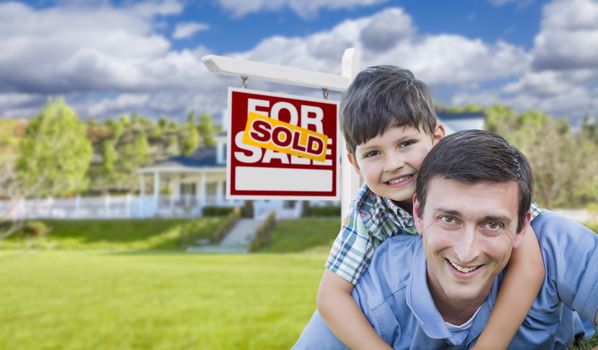 Mixed Race Father and Son Celebrating with a Piggyback in Front Their House and Sold Real Estate Sign.