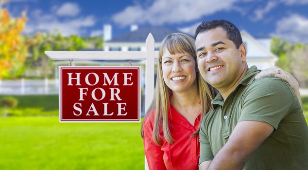 Happy Couple in Front of For Sale Real Estate Sign and New House.