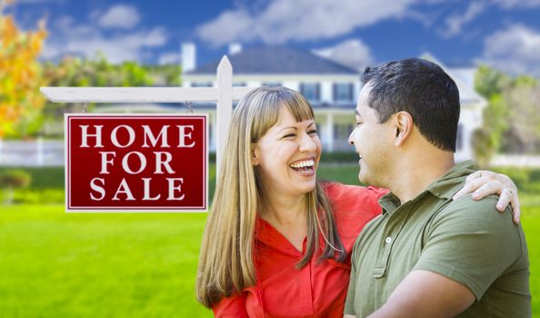 Happy Couple in Front of For Sale Real Estate Sign and New House.