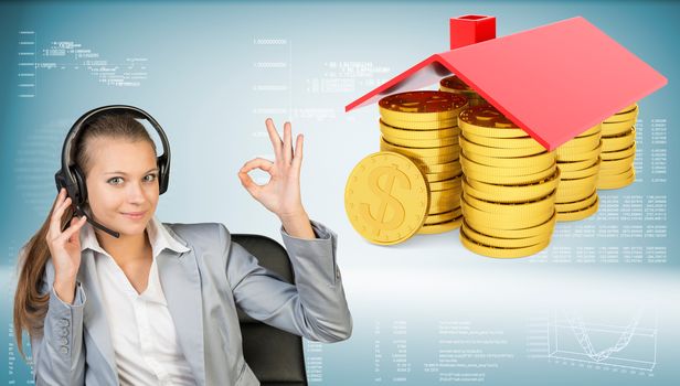 Businesswoman smiling sitting in office chair wearing headset making okay gesture with both hands. Piles of golden dollars under roof beside. Hi-tech charts with various data as backdrop