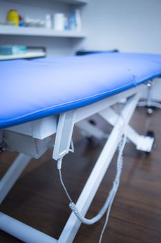 Blue physiotherapy bed in a physiotherapist's treatment area in hospital clinic. 