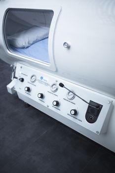 Hyperbaric Oxygen Therapy (HBOT) chamber tank used for specialised medical treatment for injuries in hospital clinic. Exterior viewing window with pillow and bed inside. 