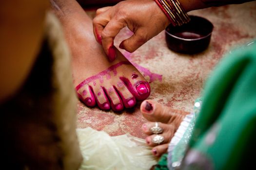 Indian groom doing marriage rituals doing colored foot fingure their mandap puja