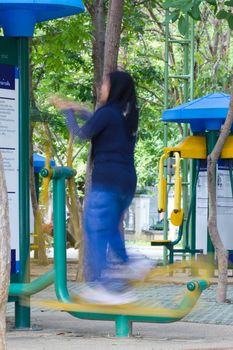 Blurred image of a woman exercising on equipment in a park in Thailand (motion blur image)