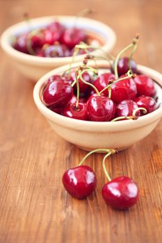 many ripe raw wet sweet cherry in dish on wooden background