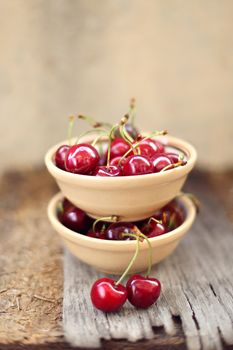 many ripe raw wet sweet cherry in dish on wooden background