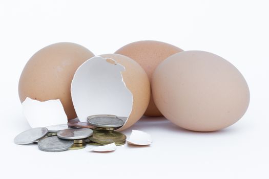 Broken egg with coins on white background