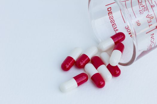 capsules with  measuring glass isolated on a white background