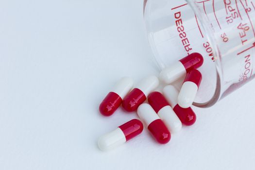 capsules with  measuring glass isolated on a white background