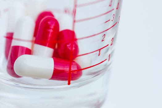 measuring glass with capsules on a white background