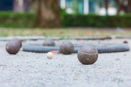 Five rusty old petanque balls and the small white jack on petanque court