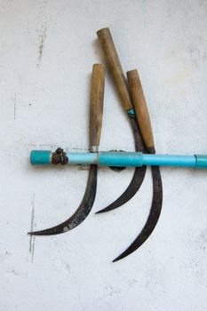 three old sickles on a wall in Thailand