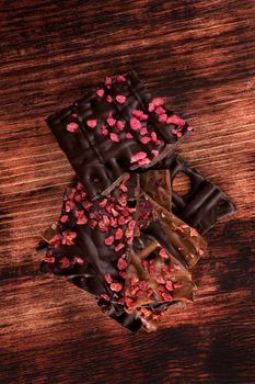 Luxurious dark and milk chocolate pieces in dark brown textured wooden background. Sweet chocolate dessert eating. 