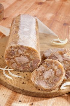 Head cheese on brown vintage cutting board with onion. Traditional culinary eating. 