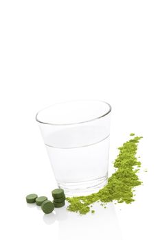 Green food supplements and a a glass of water isolated on white background. Spirulina, chlorella and young barley. Detox and detoxify.