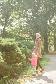 Beautiful Mother And Baby outdoors. Nature. Beauty Mum and her Child playing in Park together. Outdoor Portrait of happy family. Joy. Mom and Baby