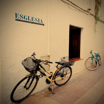 two bicycles at a white wall with arrows and labeled in Catalan "church", instagram image style
