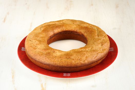 Homemade wreath cake on red plate with white background horizontal