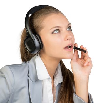 Businesswoman in headset, with her fingers on microphone boom, looking ahead and upward, her mouth open. Isolated over white background