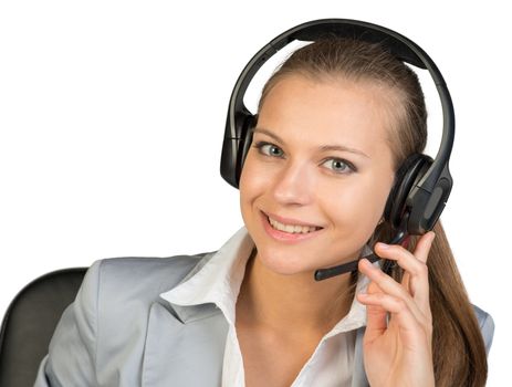 Businesswoman in headset, with her fingers on microphone boom, her head tilted slightly to the side, looking at camera, smiling. Isolated over white background