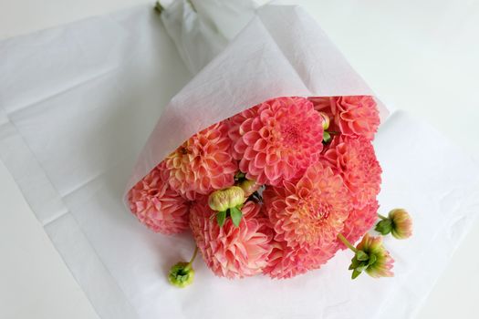 Bouquet of coral dahlias wrapped in crepe paper