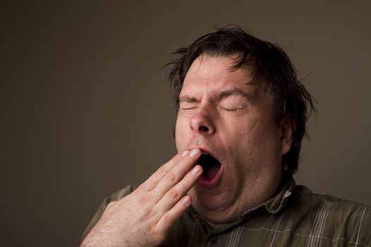 MAn lets out a huge yawn with how tired he is, or is he getting ready to sneeze