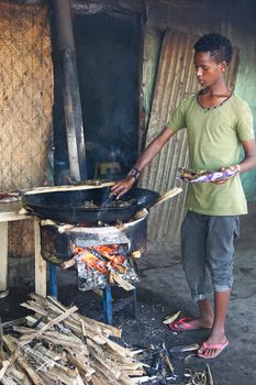 AWASSA, ETHIOPIA - NOVEMBER 16, 2014: Young Boy frying fish on the market of Awassa on November 16, 2014 in Awassa, Great Rift Valley, Ethiopia, Africa