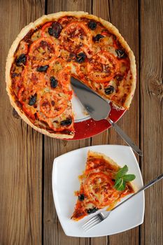 Tomato tart with olives on wooden background vertical