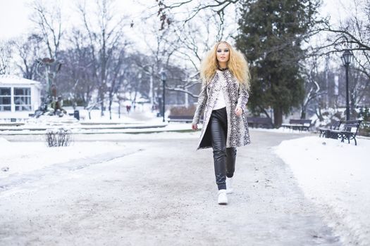 Young lady in leather pants fashion walk through the city park