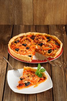 Tomato tart with olives on wooden background with space vertical