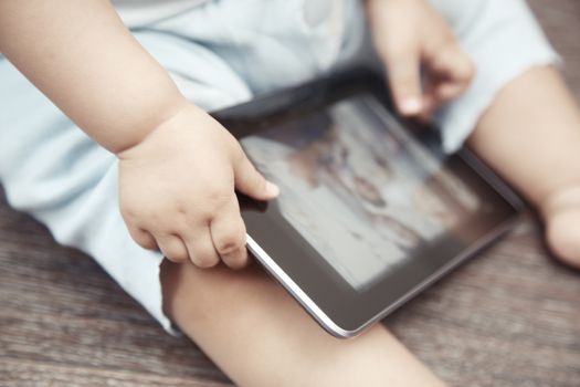 Baby with tablet computer. Close-up photo of the hands