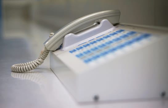 White phone to communicate in the office, placed at the front counter.                               