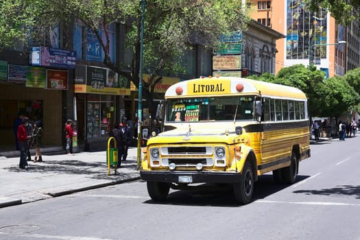 LA PAZ, BOLIVIA - OCTOBER 16, 2014: Old yellow Chevrolet bus used for public transportation driving on El Prado avenue in the city center on October 16, 2014 in La Paz, Bolivia 
