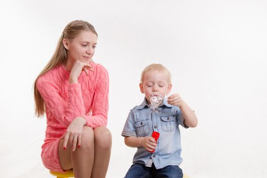 Young mother watching her son who blow bubbles