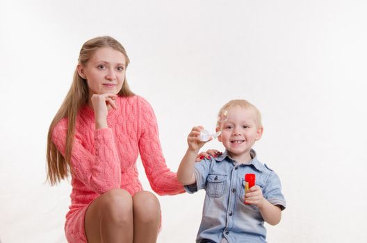Young mother watching her son who blow bubbles
