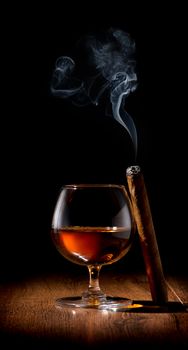 Wineglass of scotch and cigar on wooden table