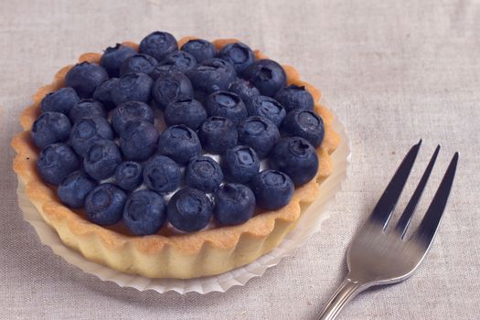 Tartlet with fresh blueberries on a wooden background 