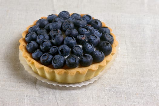 Tartlet with fresh blueberries on a wooden background 