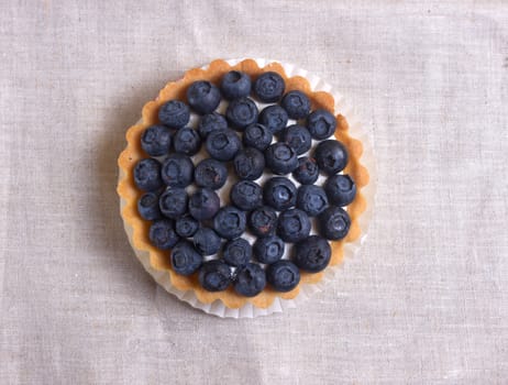 Tartlet with fresh blueberries on a wooden background 