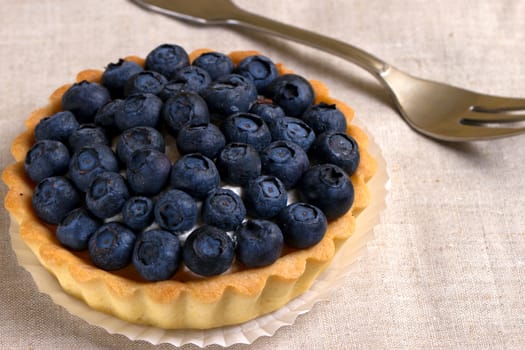 Tartlet with fresh blueberries on a wooden background 