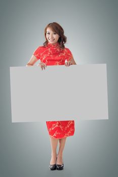 Attractive Chinese woman dress traditional cheongsam and hold blank board, full length portrait.