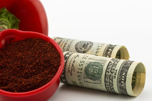 Red chili powder spice in crimson bowl with pepper in background and American currency in foreground