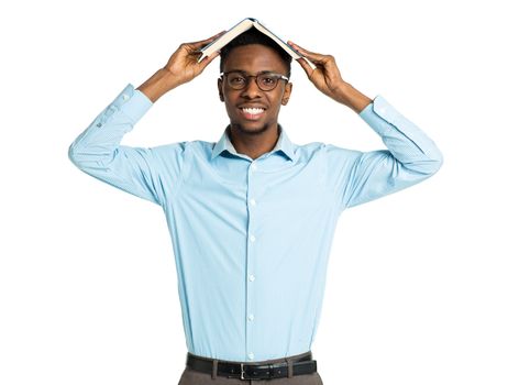 Happy african american college student standing with book on his head on white background