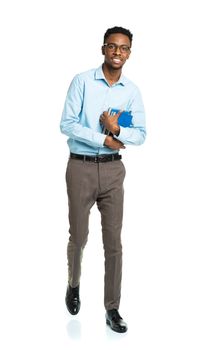 Happy african american college student standing with books in his hands on white background