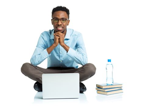 Happy african american college student sitting with laptop on white background