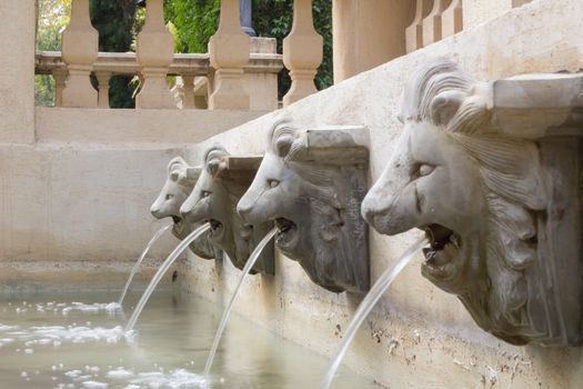 water flow from statue head of lion in public park in Thailand