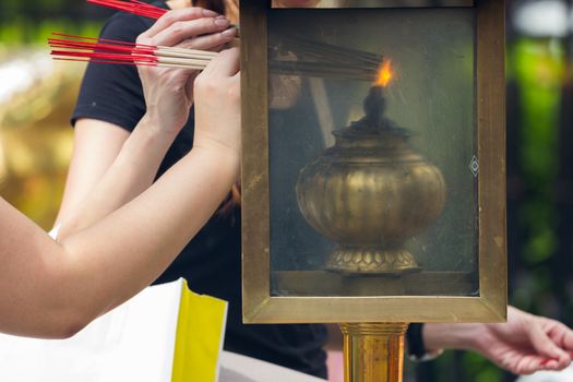 people lighting Incense sticks with lamp in Thailand