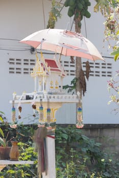 white spirit house in thailand with old umbrella