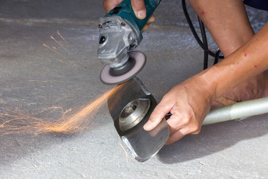 hand of man sharpening blade of mowing machine with angle-grinder