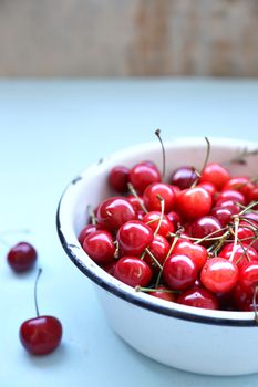 many ripe raw wet sweet cherry in dish on wooden background